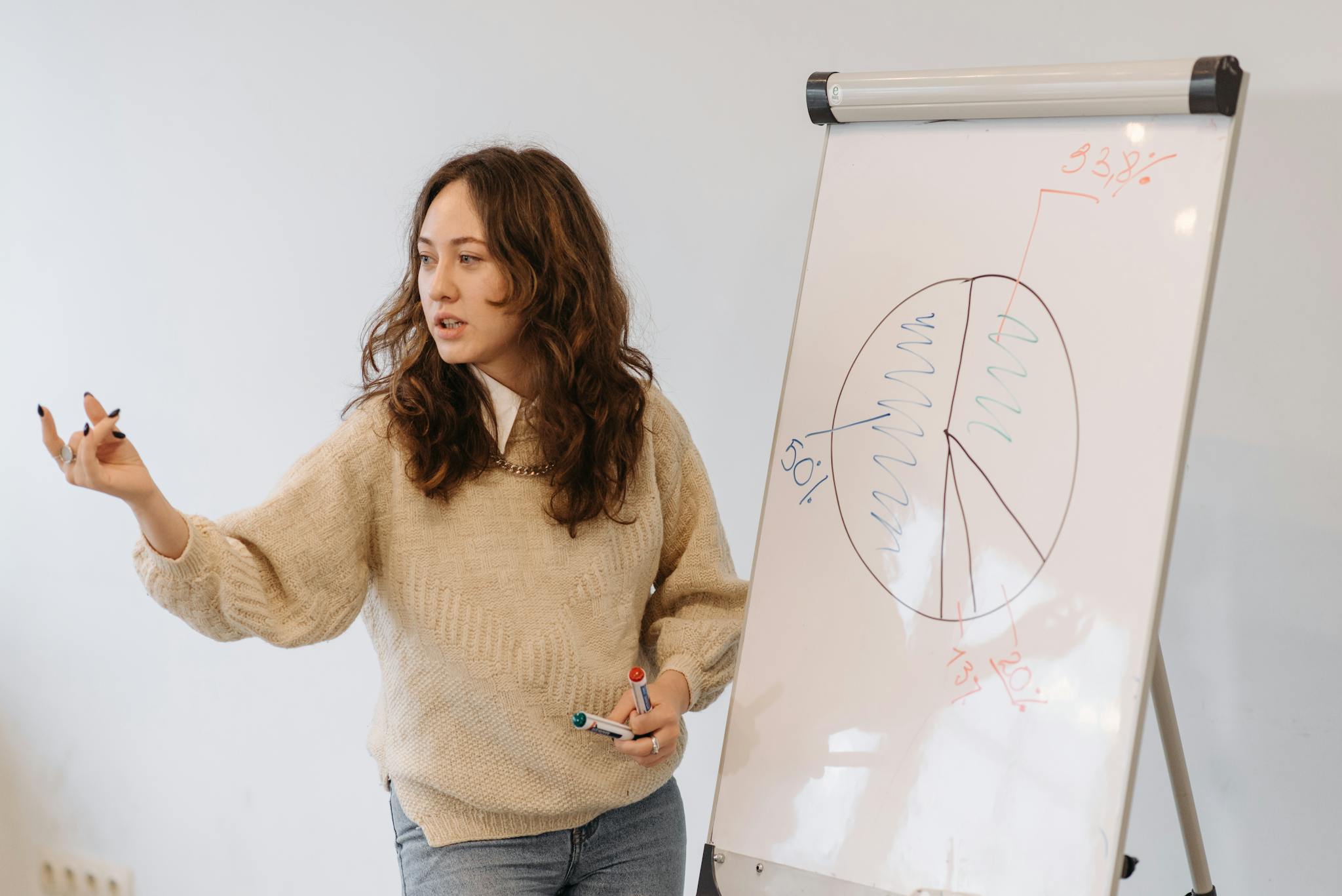 Woman gives presentation with pie chart on whiteboard, explaining data analysis.